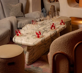 Marble coffee table set with wine glasses and small desserts in a stylish lounge seating area.