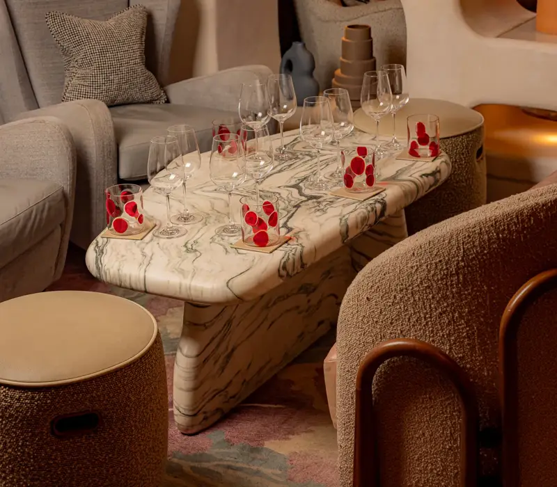 Marble coffee table set with wine glasses and small desserts in a stylish lounge seating area.
