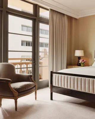 Bedroom in the Beverly Three-Bedroom Residence, designed with neutral tones, luxurious bedding, and full-height windows.