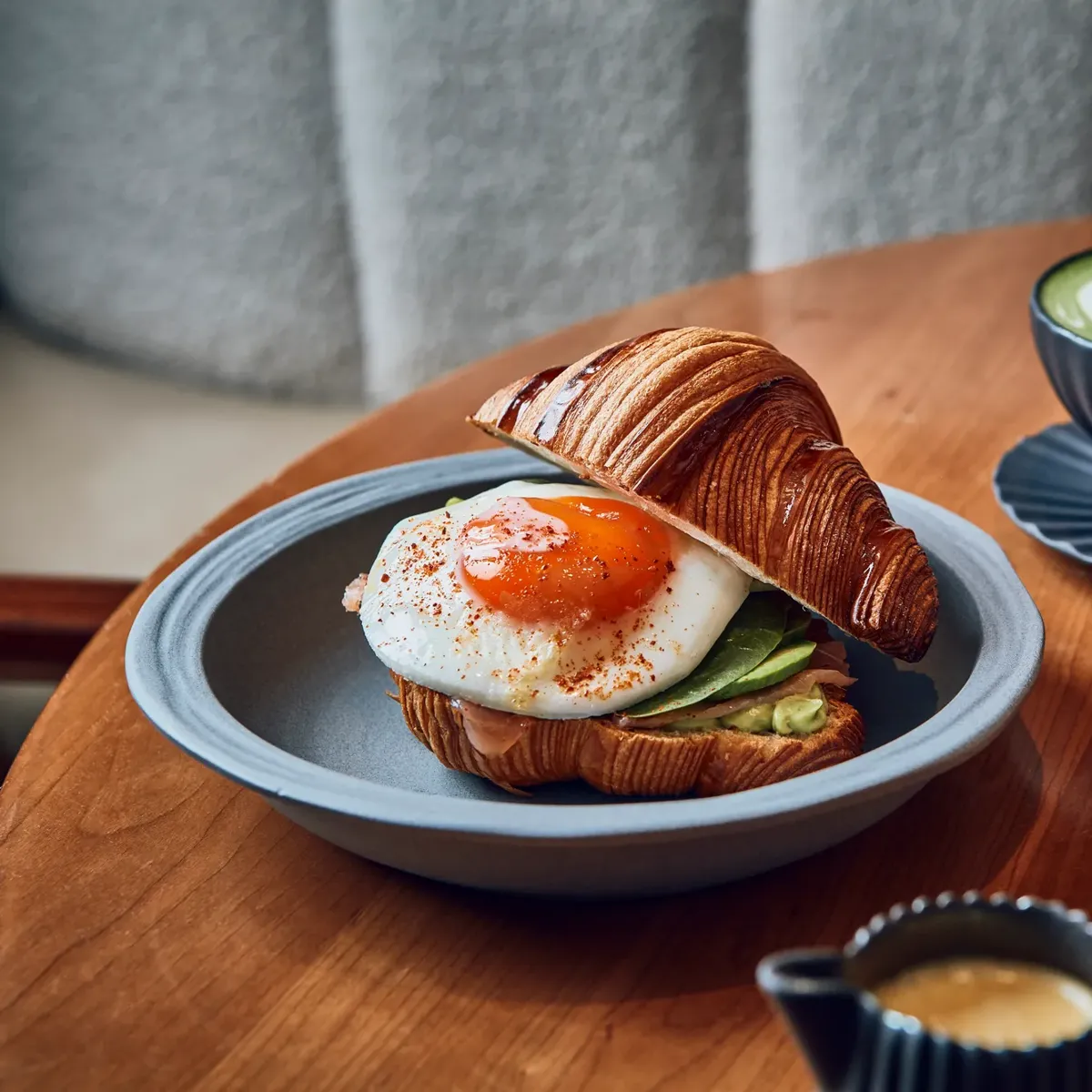 Salty breakfast croissant as well as matcha on a wooden table