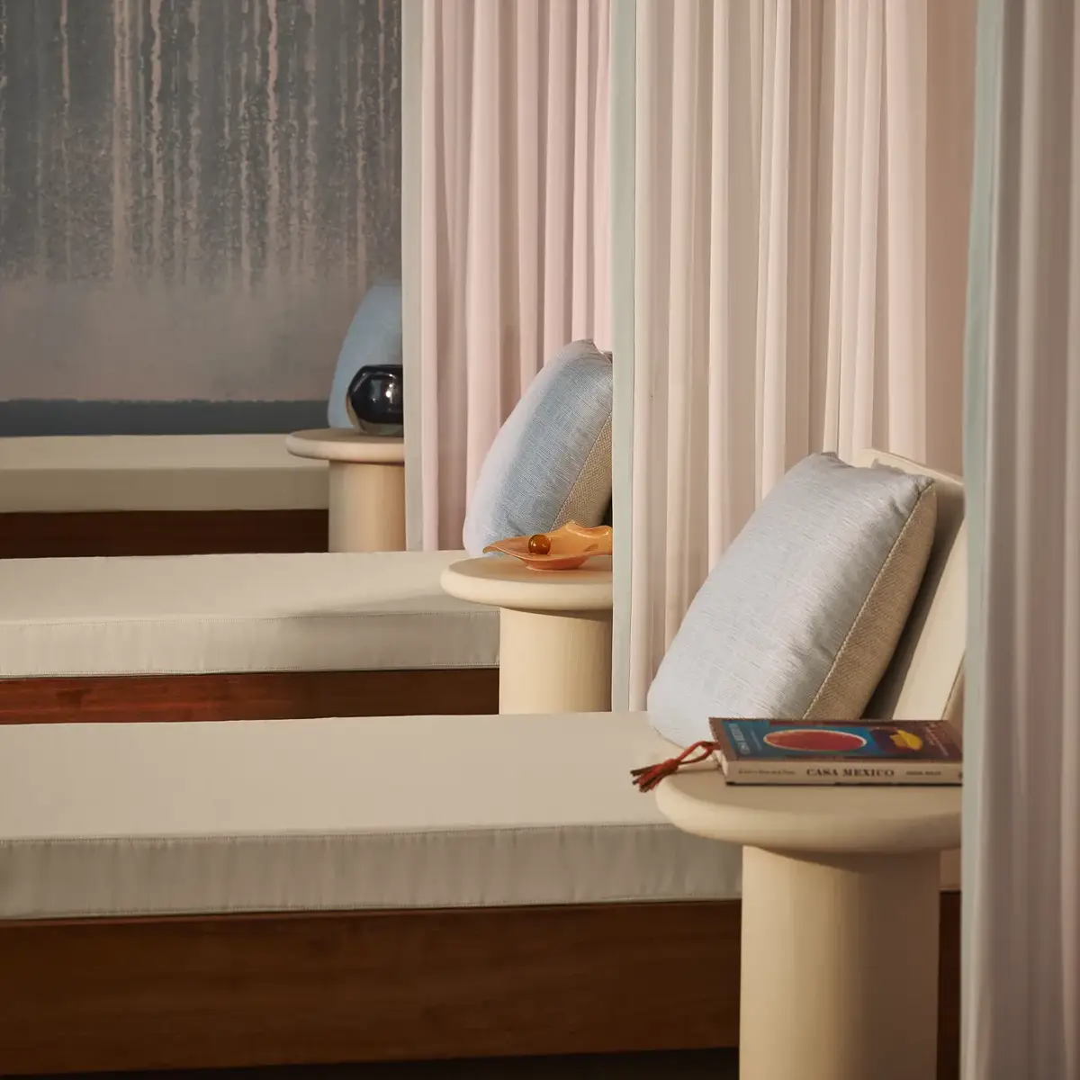 Relaxation lounge with cushioned daybeds, soft curtains, and side tables, creating a tranquil spa atmosphere.