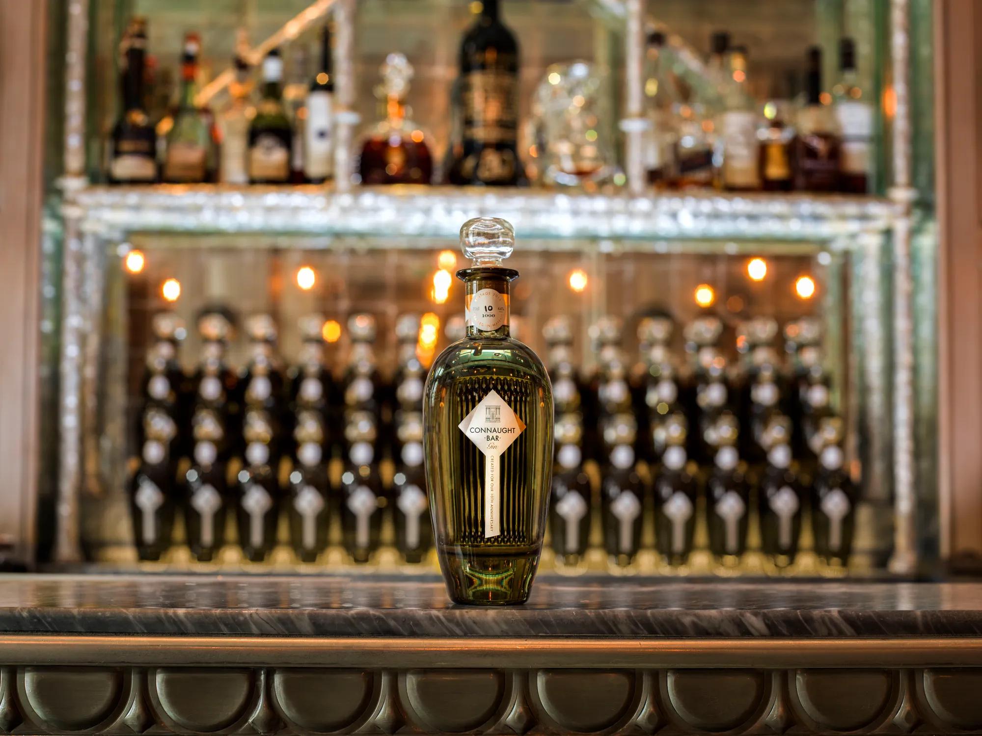 Connaught Bar bottle displayed on marble counter before illuminated back bar shelves.