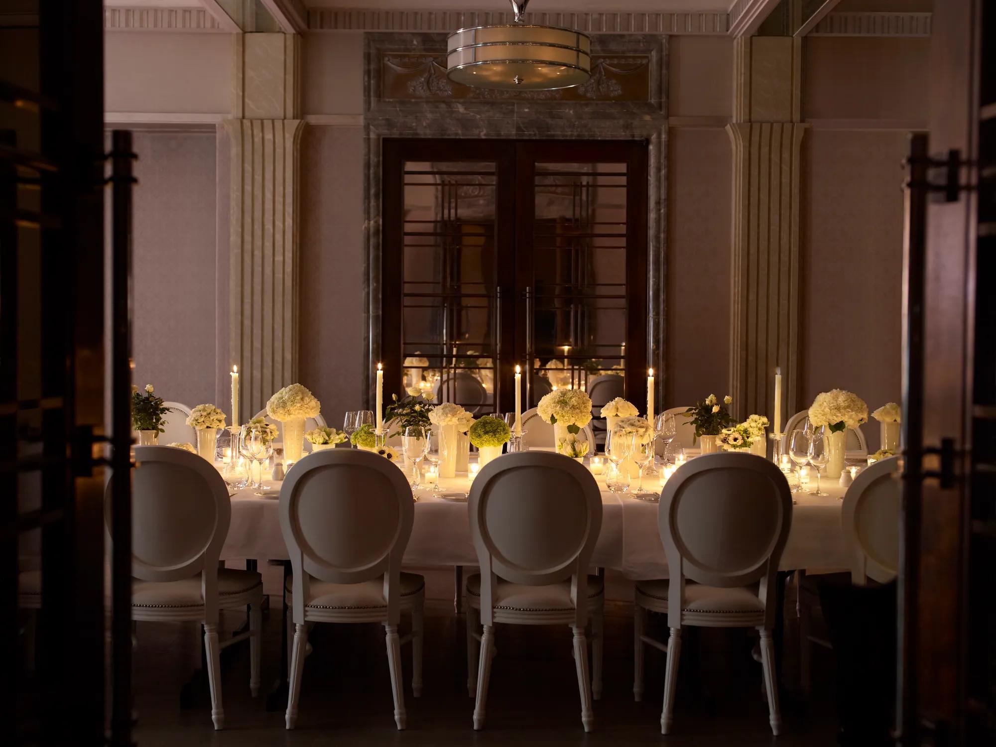 Candlelit private dining table with white floral centerpieces and elegant place settings.