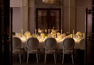 Candlelit private dining table with white floral centerpieces and elegant place settings.