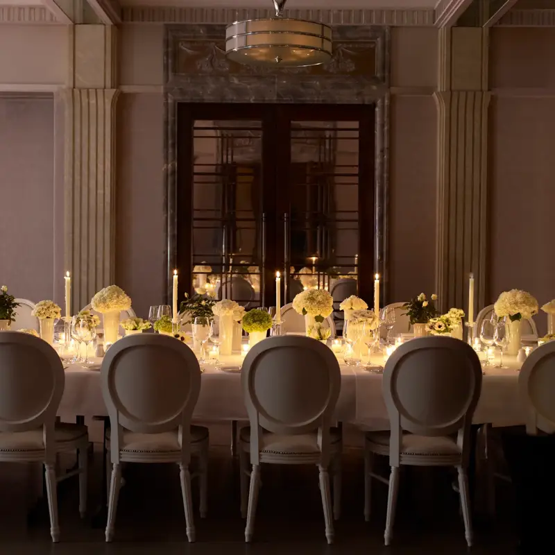 Candlelit private dining table with white floral centerpieces and elegant place settings.