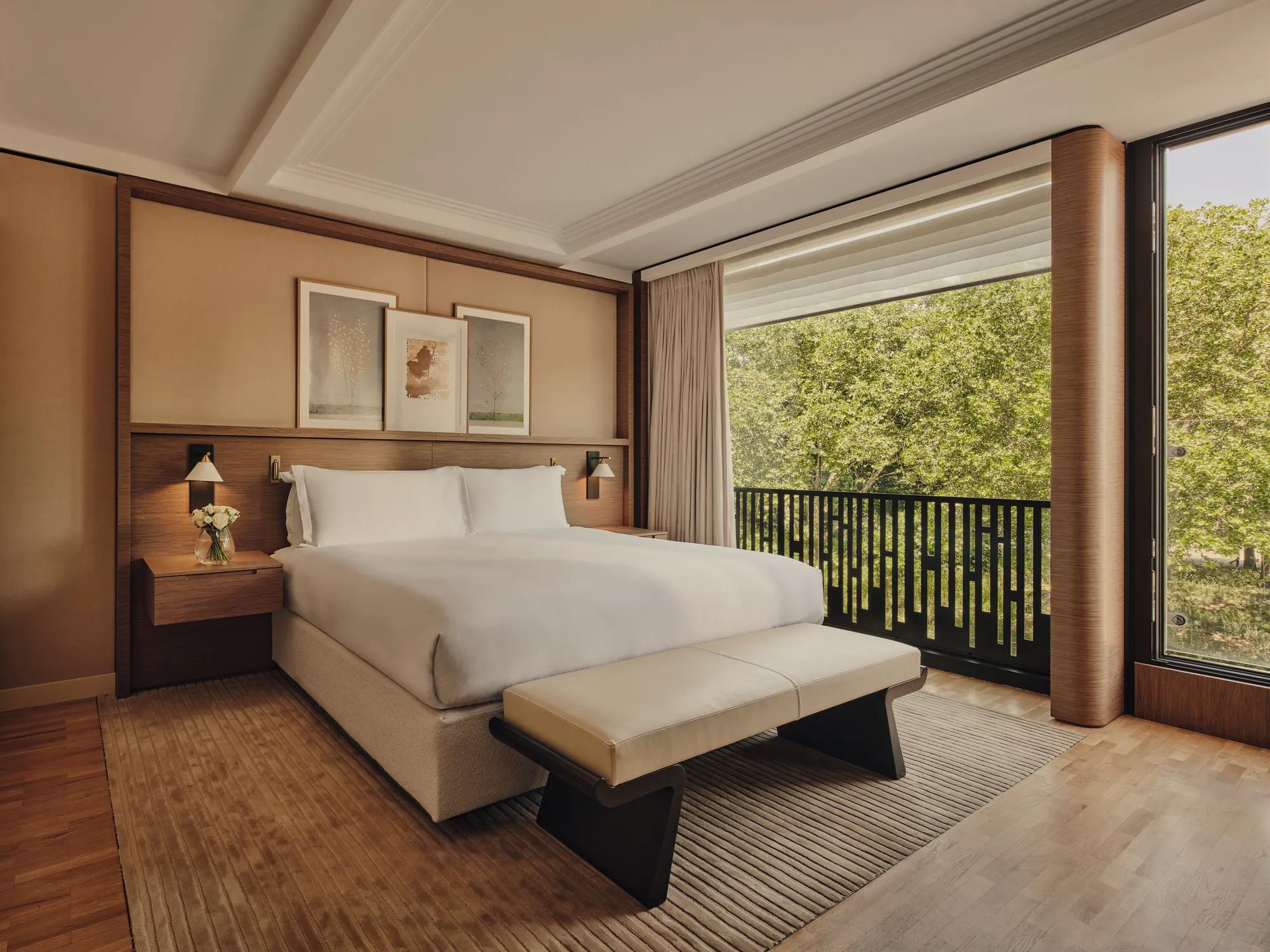 A large bed in a bedroom overlooking a park