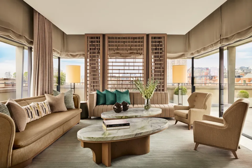 Bright living room with marble coffee tables, neutral sofas, green accent cushions, and city views through floor-to-ceiling windows