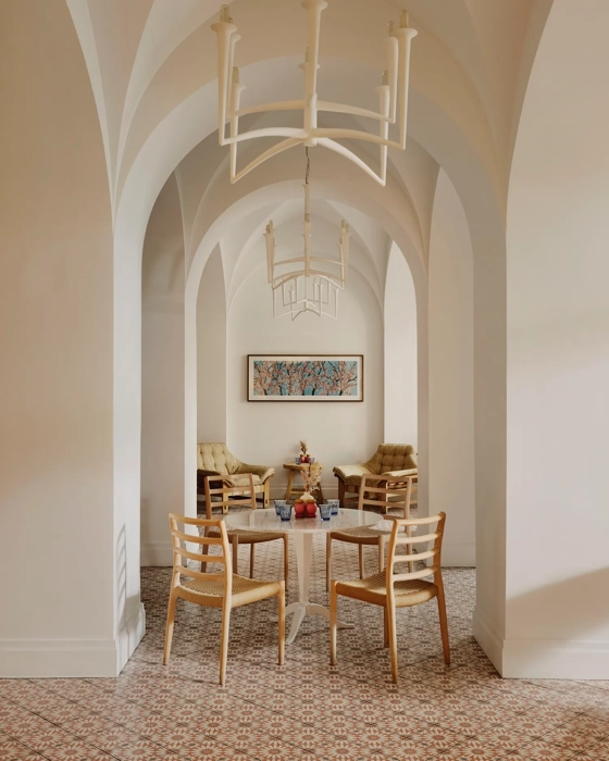 Arched café corridor with chandeliers, small round tables, and a lounge seating area at the far end.