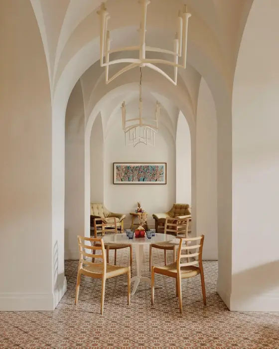Arched café corridor with chandeliers, small round tables, and a lounge seating area at the far end.