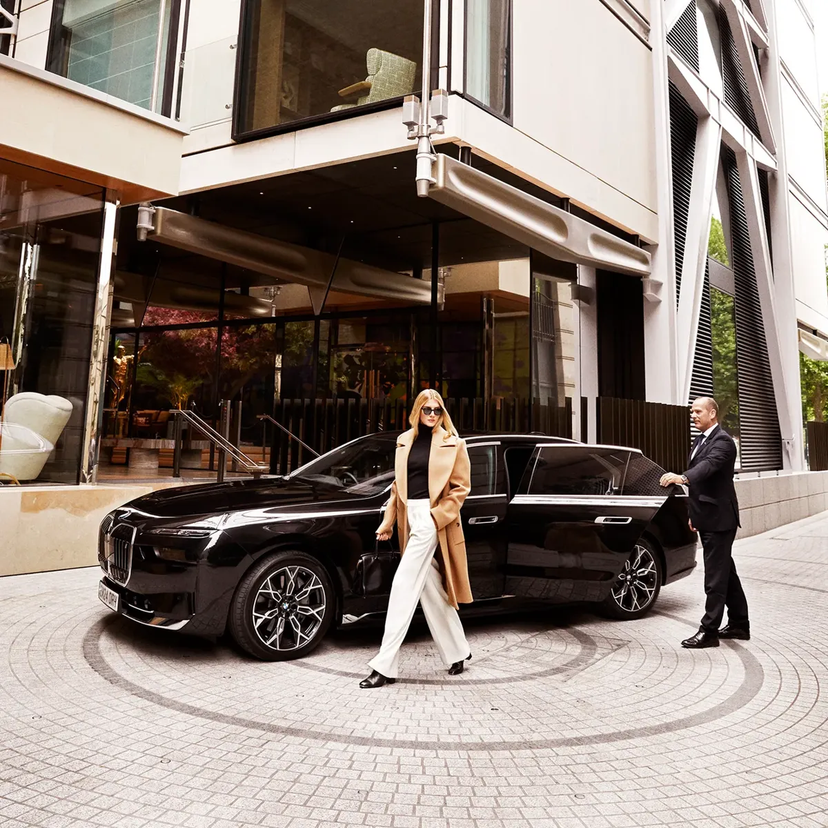 Guest exits black BMW outside The Emory entrance, greeted by a doorman in formal attire.