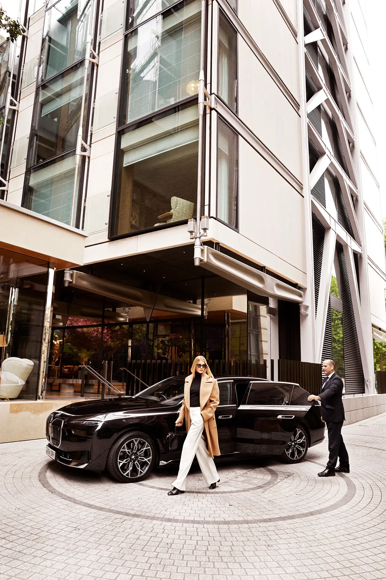 Guest exits black BMW outside The Emory entrance, greeted by a doorman in formal attire.