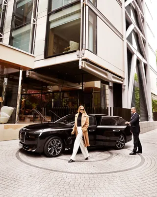 Guest exits black BMW outside The Emory entrance, greeted by a doorman in formal attire.