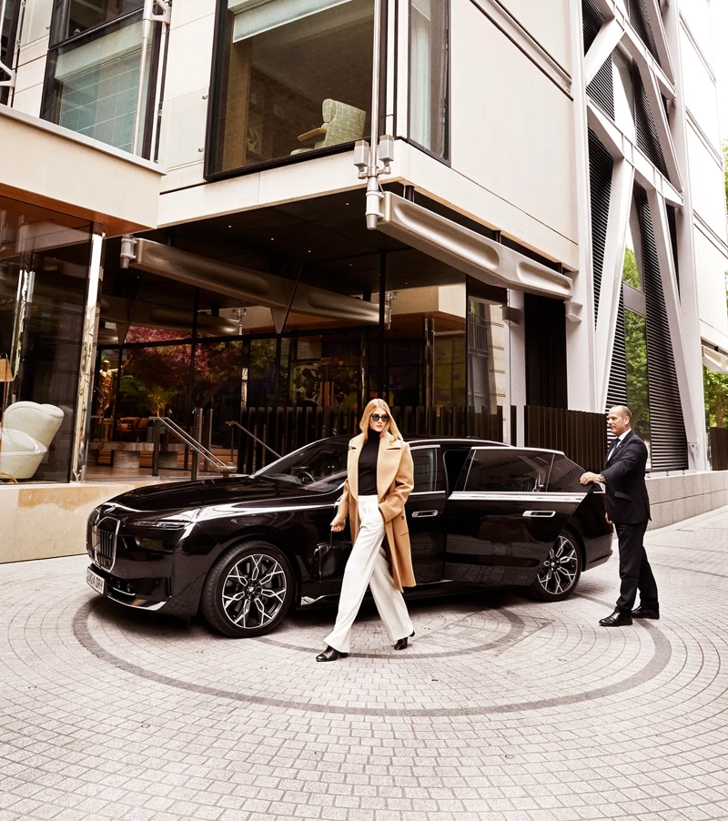 Guest exits black BMW outside The Emory entrance, greeted by a doorman in formal attire.