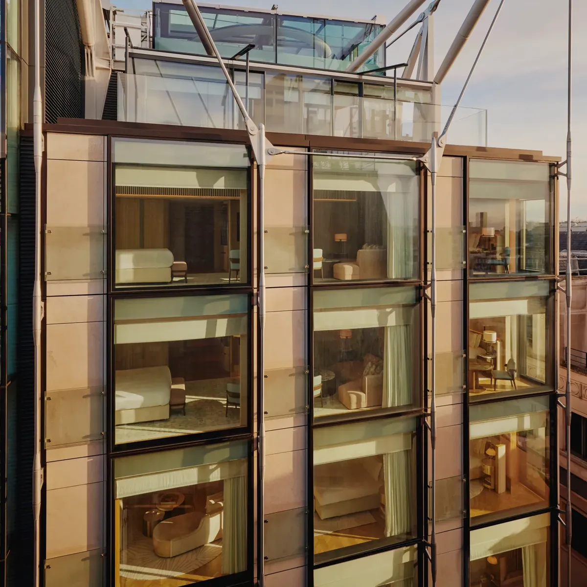 Glass-fronted façade of The Emory showing multiple suite levels, rooftop terrace, and exposed structural supports.