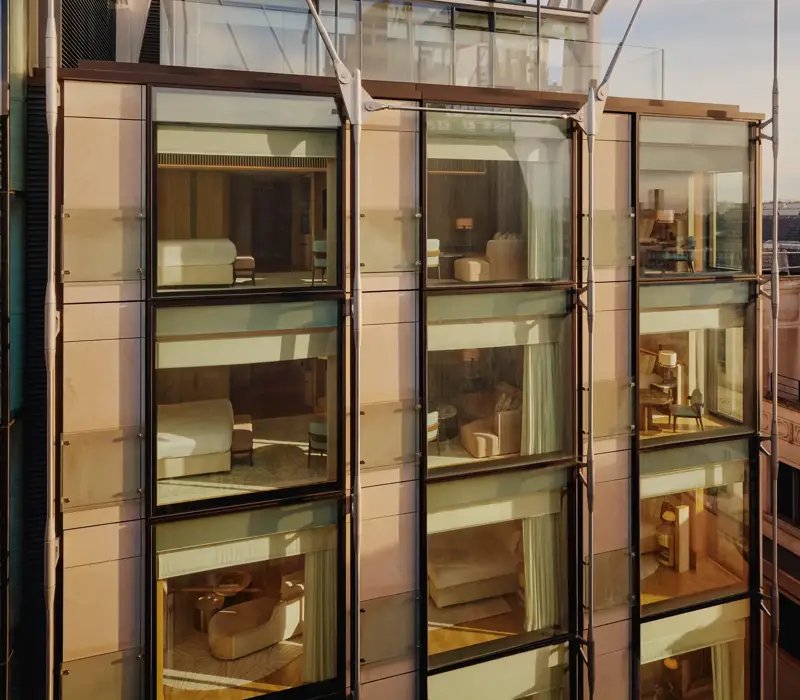 Glass-fronted façade of The Emory showing multiple suite levels, rooftop terrace, and exposed structural supports.