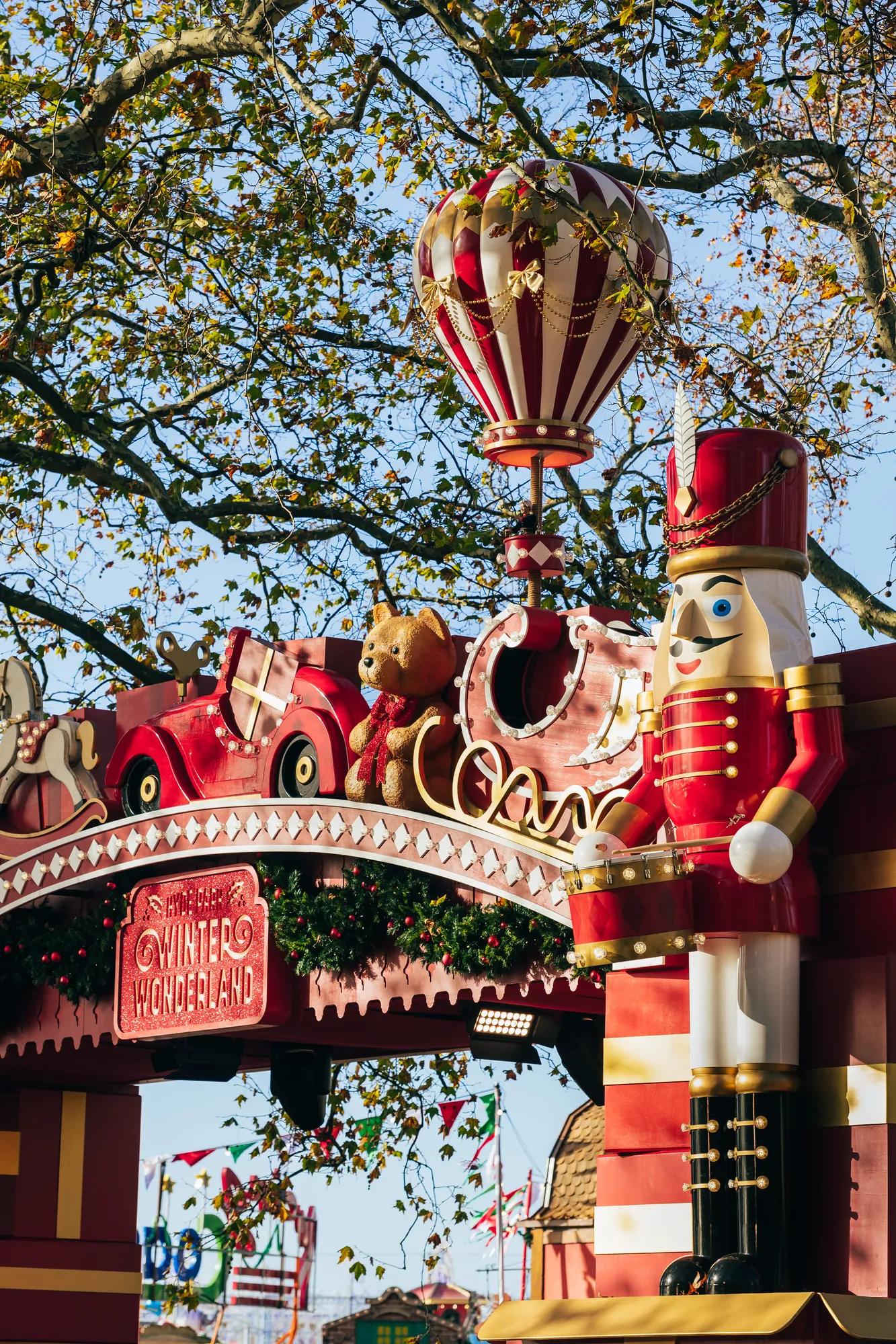 Festive winter attraction entrance decorated with a toy soldier, teddy bear, vintage car and hot air balloon.