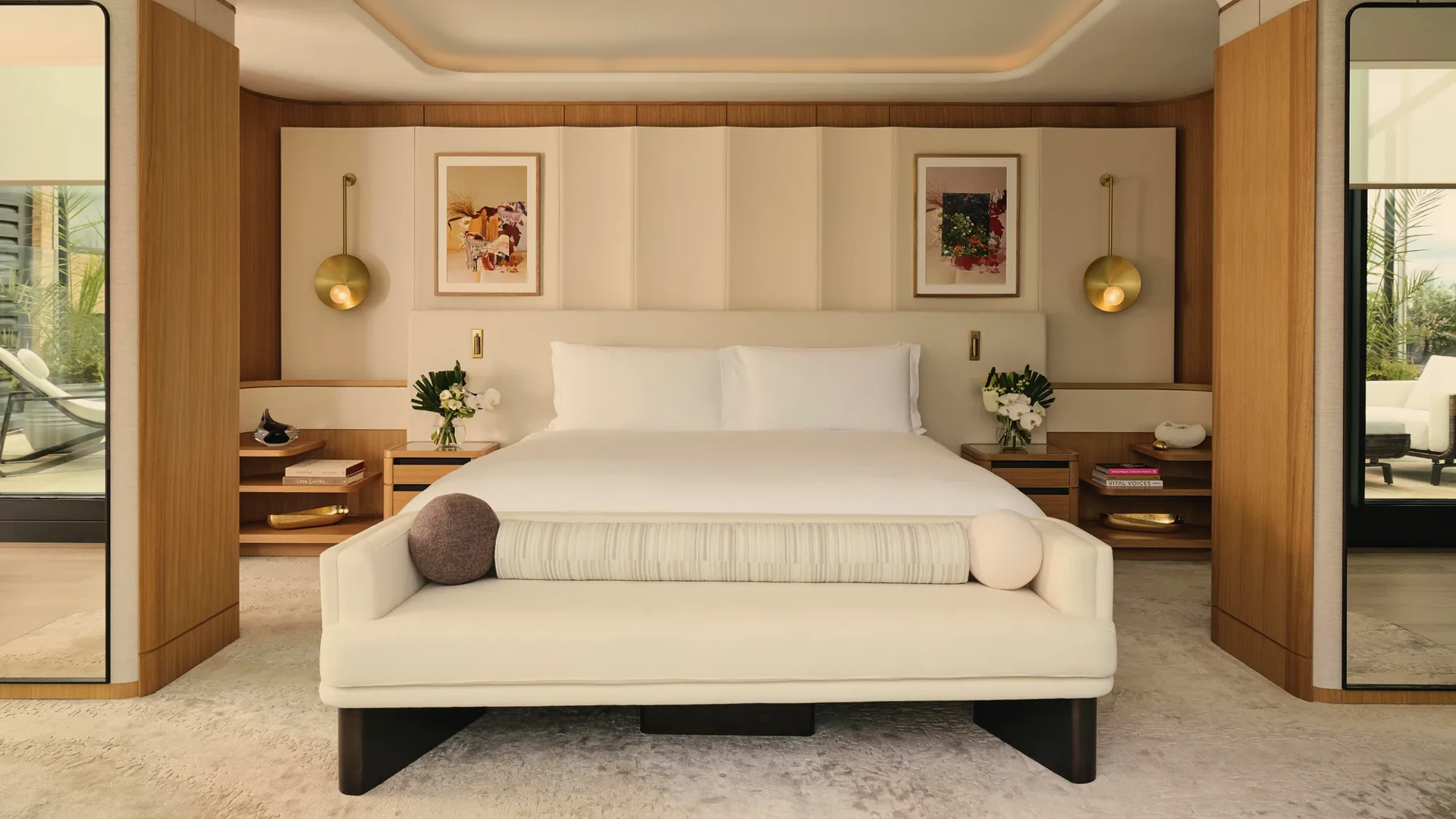 ChatGPT said:

A contemporary bedroom with a large bed, soft neutral tones, brass lighting, and wood accents opening onto a private terrace.