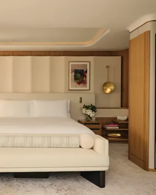 ChatGPT said:

A contemporary bedroom with a large bed, soft neutral tones, brass lighting, and wood accents opening onto a private terrace.