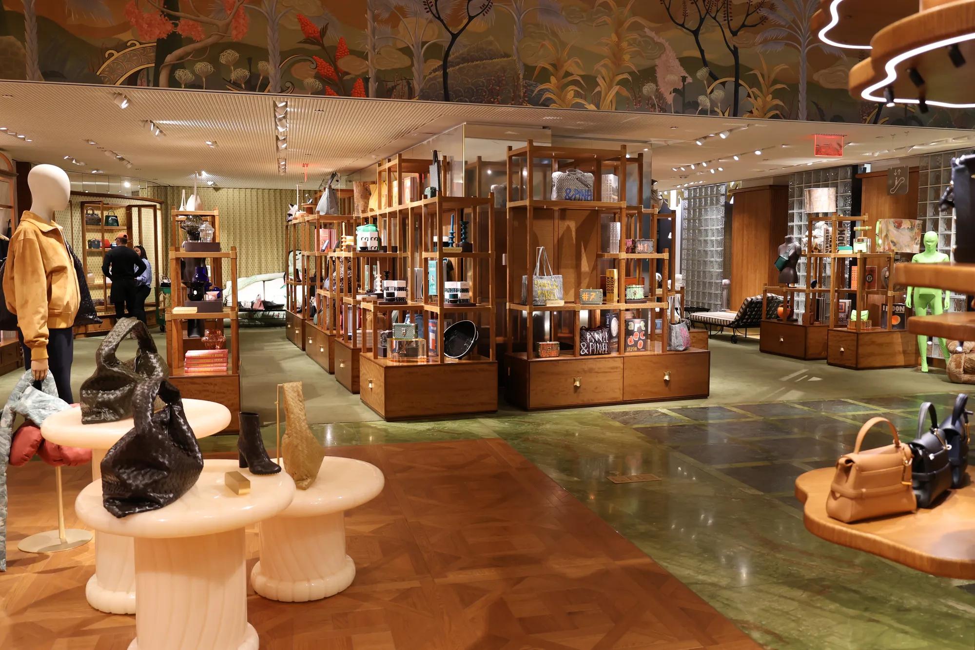 Luxury retail store interior with wooden display shelves, handbags, accessories, decorative mural ceiling, and polished flooring throughout the showroom.