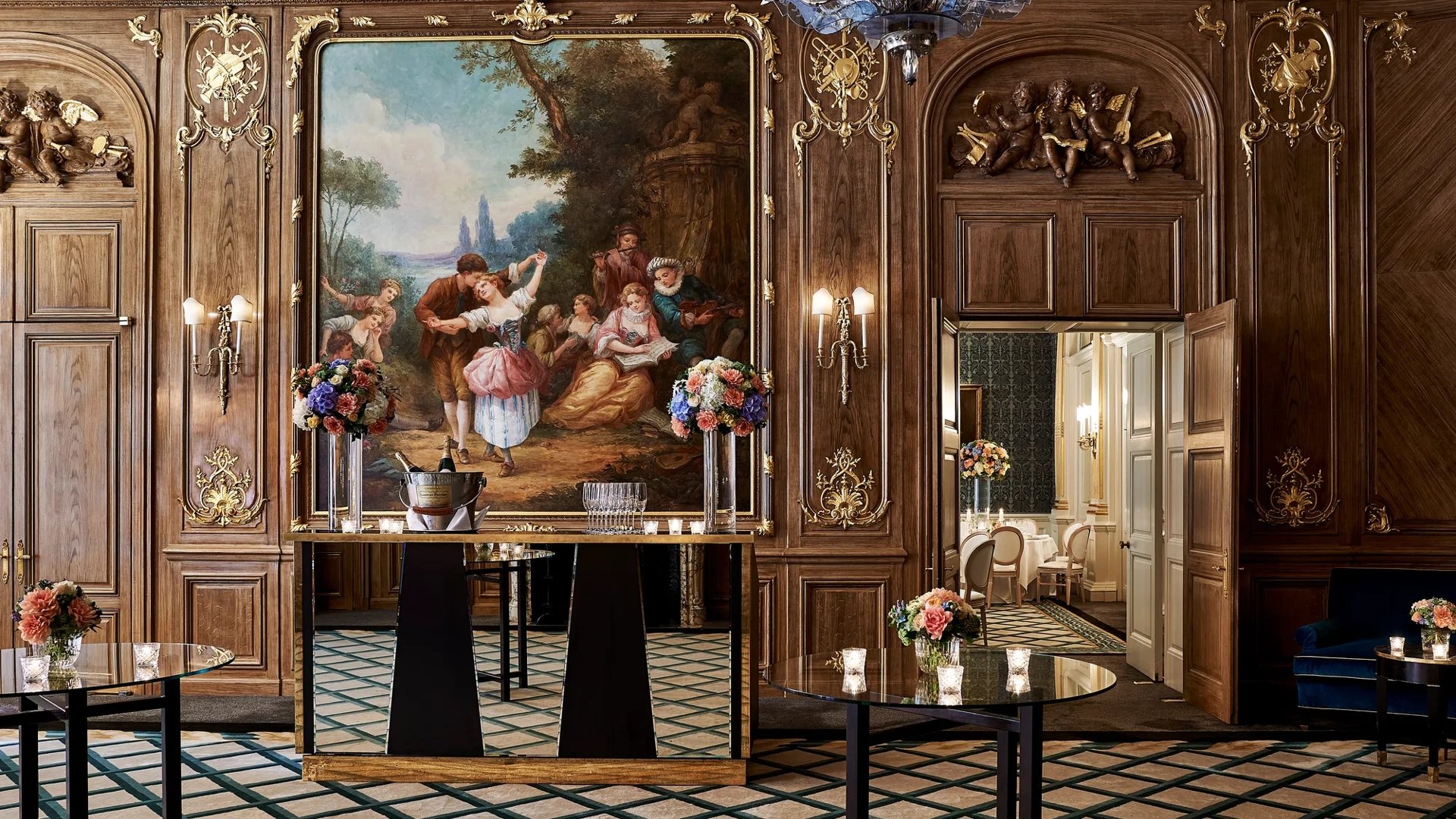 Elegant Claridge’s ballroom set for a reception with tall cocktail tables, floral centrepieces, and a mirrored bar positioned beneath a large classical painting framed in gold within the wood-panelled walls.