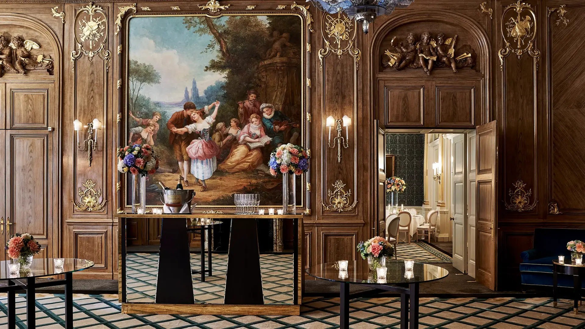 Elegant Claridge’s ballroom set for a reception with tall cocktail tables, floral centrepieces, and a mirrored bar positioned beneath a large classical painting framed in gold within the wood-panelled walls.