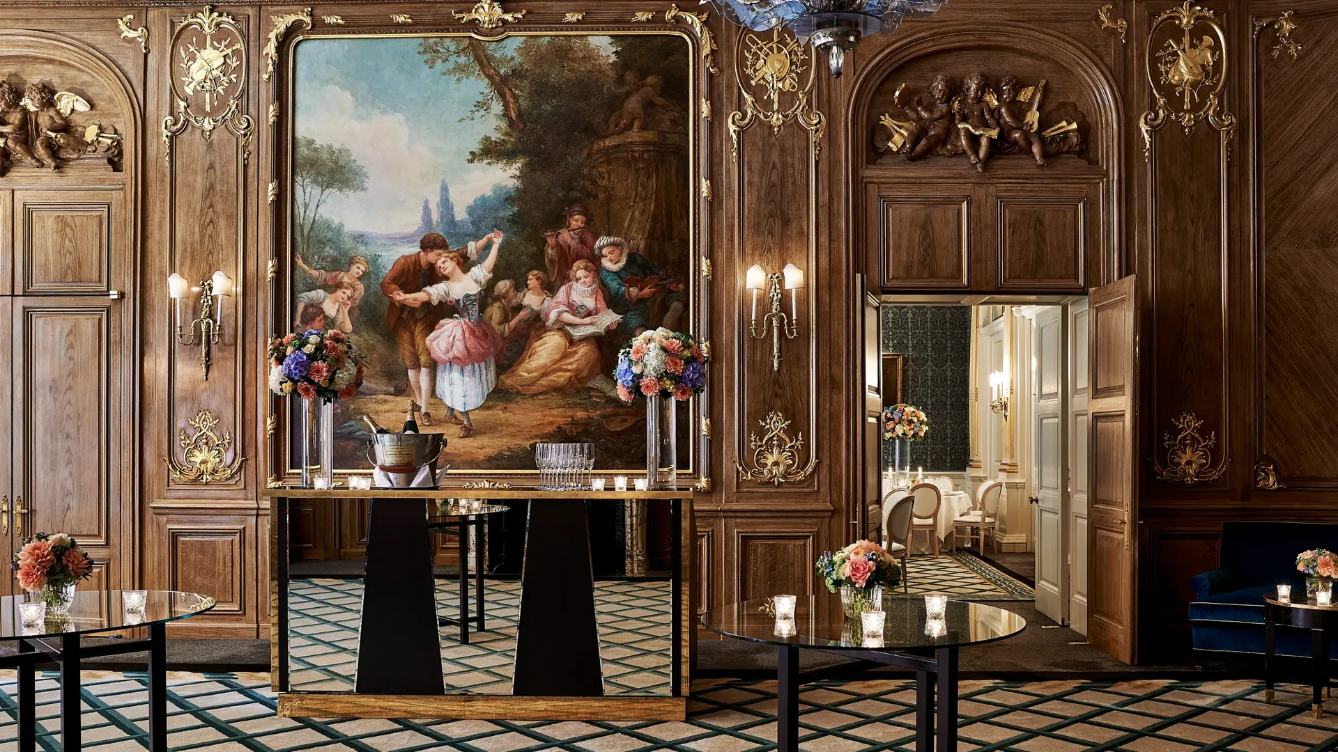 Elegant Claridge’s ballroom set for a reception with tall cocktail tables, floral centrepieces, and a mirrored bar positioned beneath a large classical painting framed in gold within the wood-panelled walls.