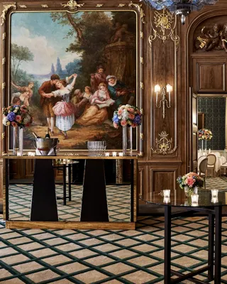 Elegant Claridge’s ballroom set for a reception with tall cocktail tables, floral centrepieces, and a mirrored bar positioned beneath a large classical painting framed in gold within the wood-panelled walls.