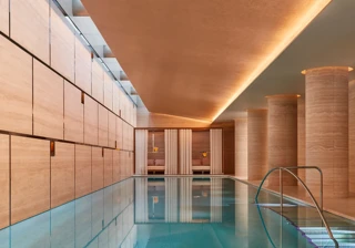 A serene spa room with soft lighting, neutral tones, and neatly folded towels on a massage bed.A serene spa room with soft lighting, neutral tones.