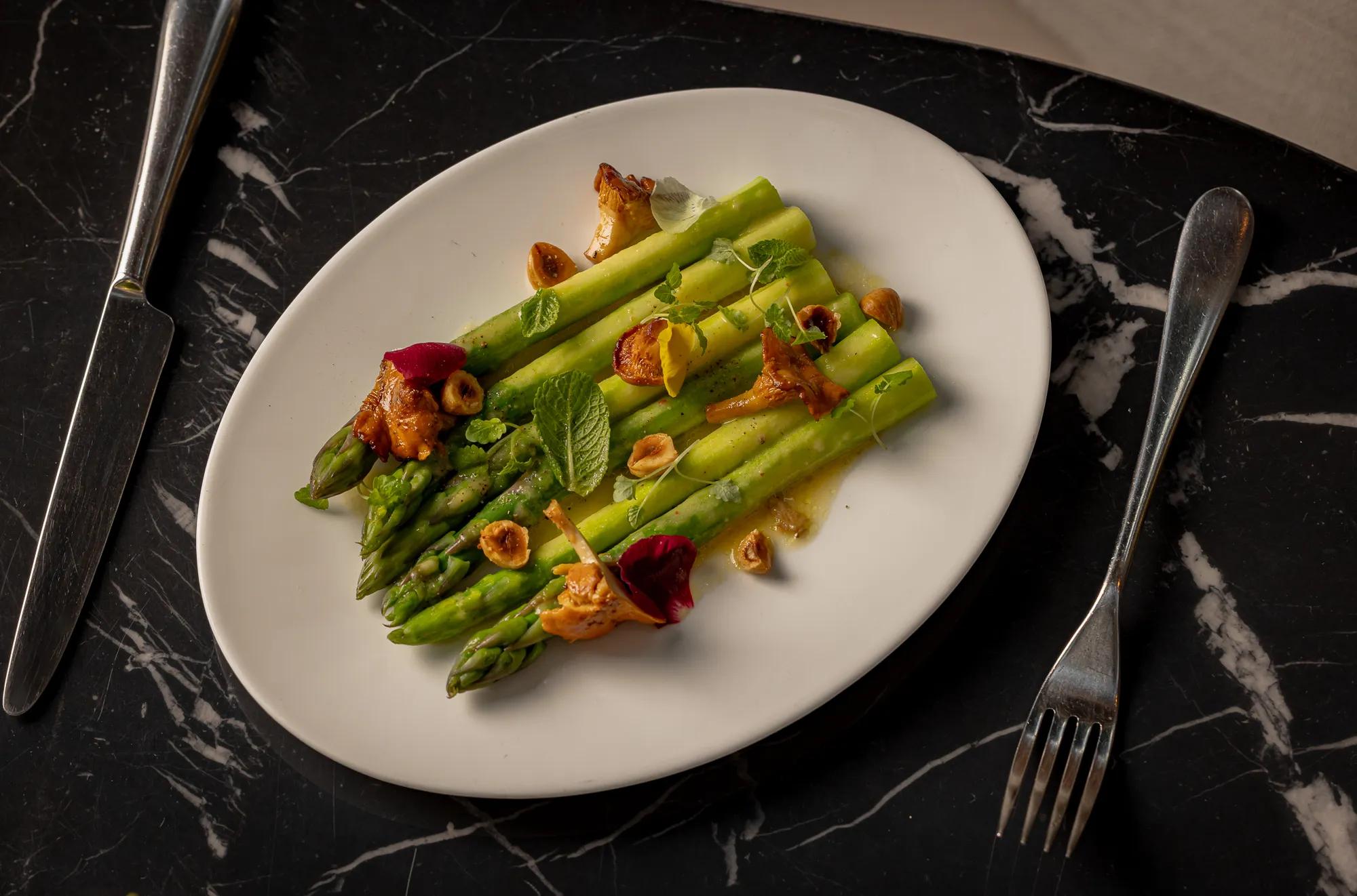 White plate filled with cooked asparagus spears set on a polished black marble countertop.