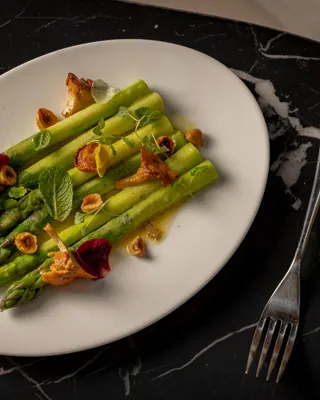 White plate filled with cooked asparagus spears set on a polished black marble countertop.