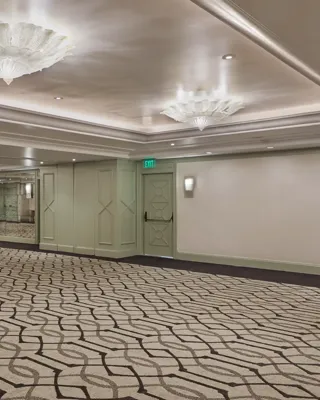 The Gallery event salon—expansive room with patterned carpet, mint doors, mirrors, and scalloped glass ceiling lights.