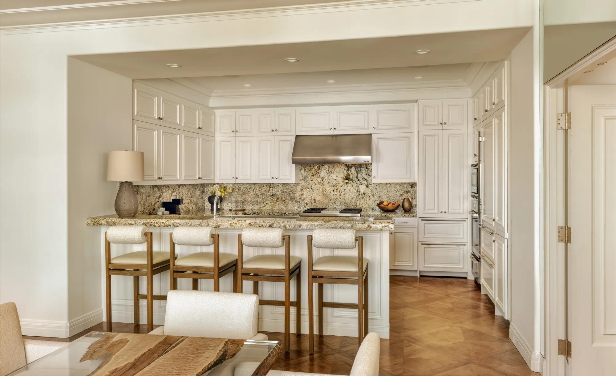 Spacious, contemporary living area in The Maybourne Three-Bed Residence Wilshire, featuring floor-to-ceiling windows, a plush sofa set, and a dining table with modern lighting.