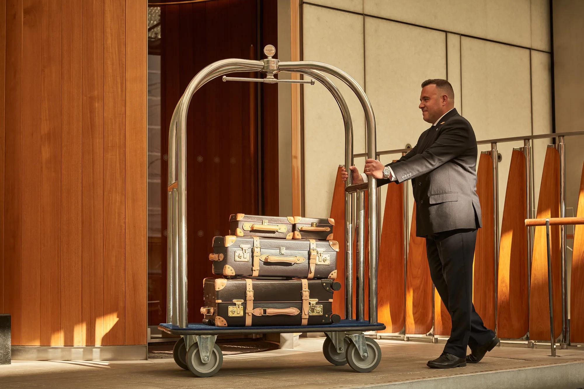 Person carrying suitcases while walking forward, holding one in each hand.