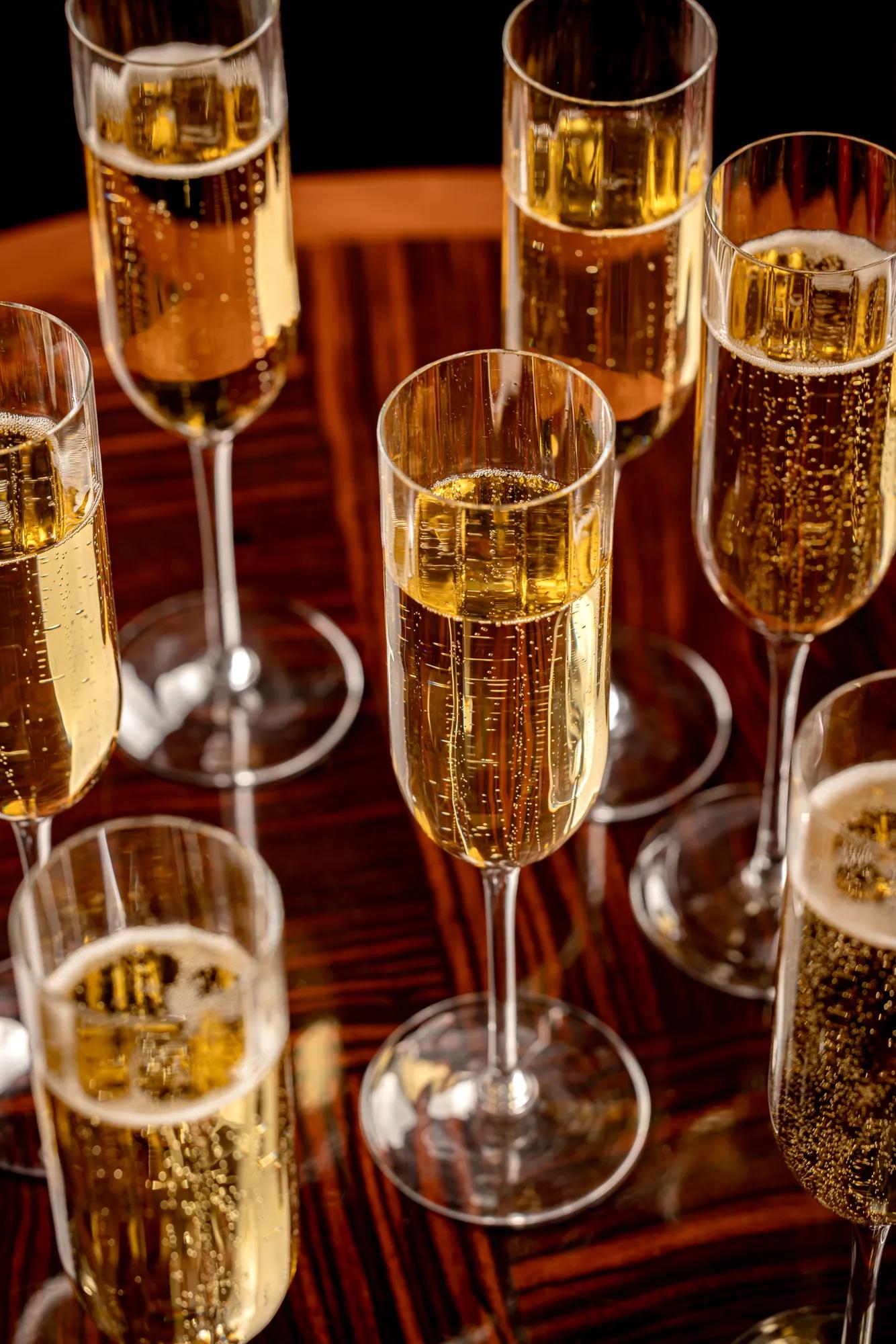 Close-up of champagne flutes filled with sparkling wine on a polished wooden table.