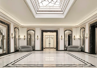 The Ballroom reception area at Claridge’s featuring polished marble floors, mirrored Art Deco wall panels, grey velvet sofas, and a large geometric skylight ceiling.