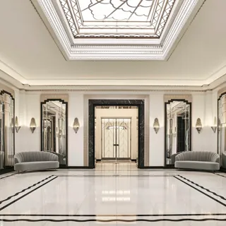 The Ballroom reception area at Claridge’s featuring polished marble floors, mirrored Art Deco wall panels, grey velvet sofas, and a large geometric skylight ceiling.