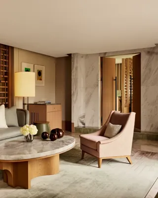 Elegant sitting area with marble coffee table, grey sofa, pink armchairs, and wooden lattice wall panels