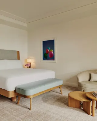 Detail of a king-size bed with plush white linens and textured headboard.