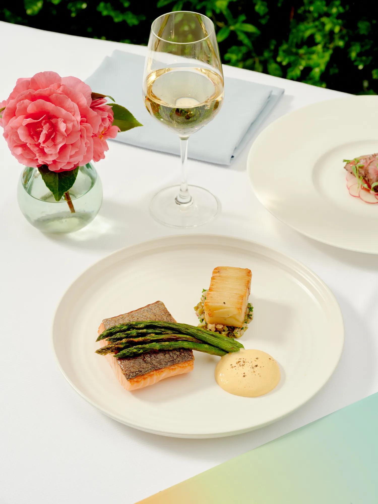 Grilled salmon with asparagus, potato, and hollandaise sauce beside a glass of white wine at The Terrace restaurant.