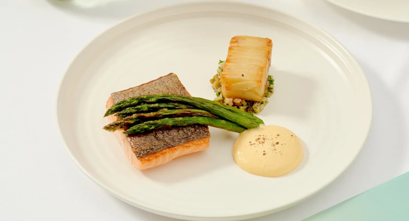 Grilled salmon with asparagus, potato, and hollandaise sauce beside a glass of white wine at The Terrace restaurant.