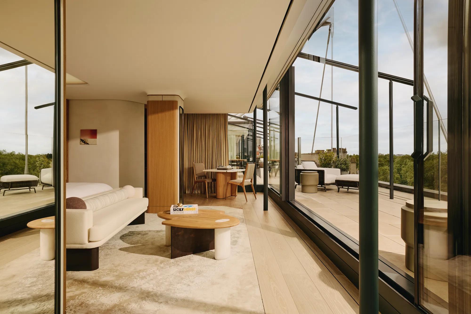 Bright suite living area with cream furnishings, floor-to-ceiling glass, and private terrace access.