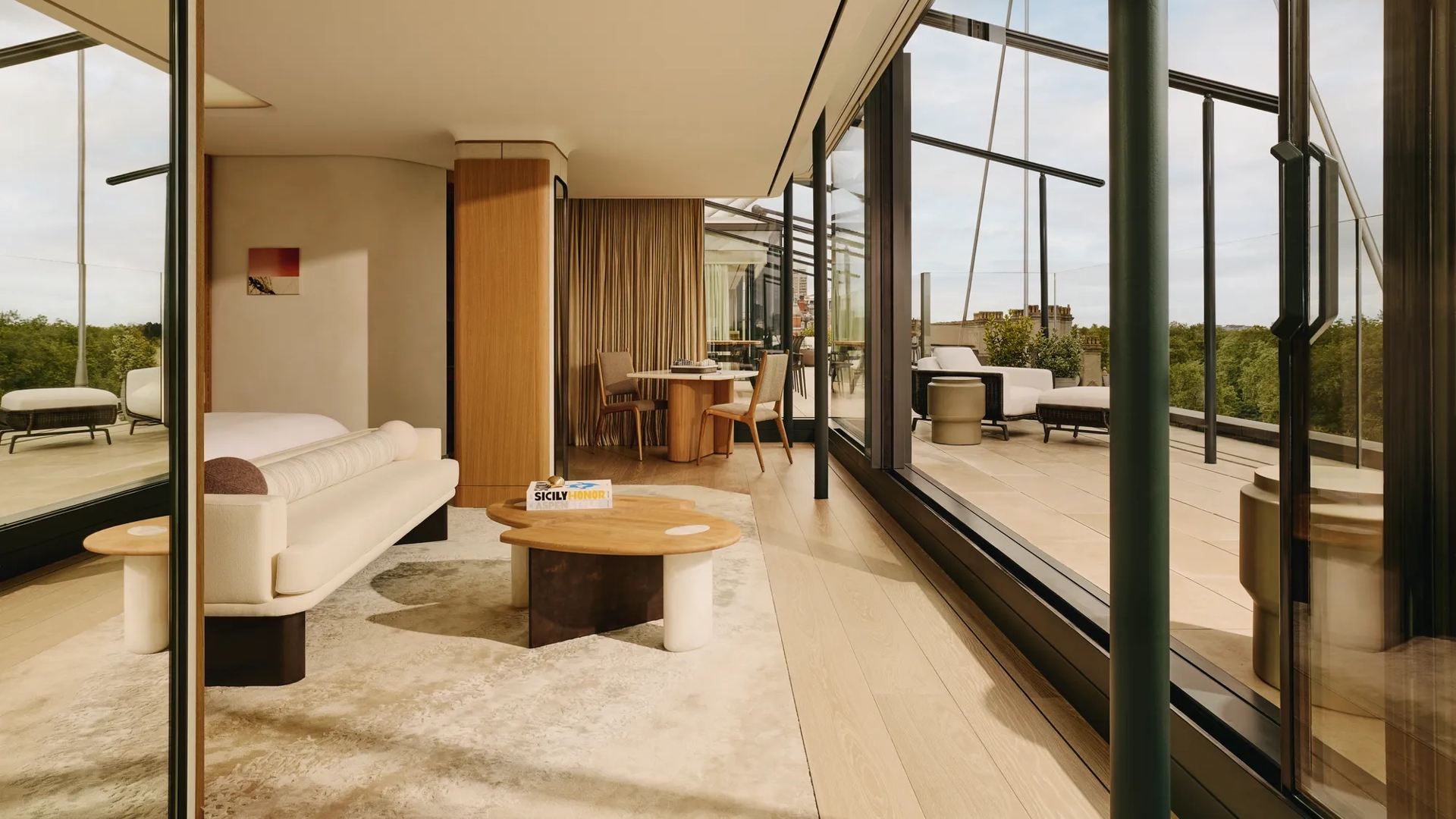 Bright suite living area with cream furnishings, floor-to-ceiling glass, and private terrace access.