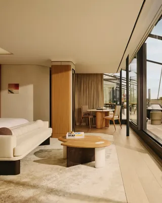 Bright suite living area with cream furnishings, floor-to-ceiling glass, and private terrace access.