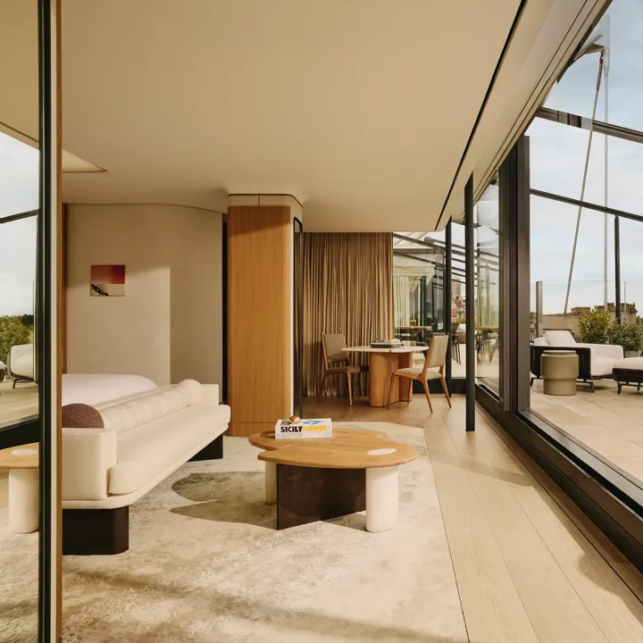 Bright suite living area with cream furnishings, floor-to-ceiling glass, and private terrace access.