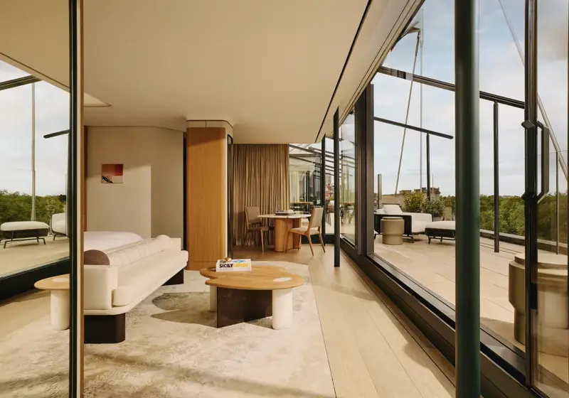 Bright suite living area with cream furnishings, floor-to-ceiling glass, and private terrace access.