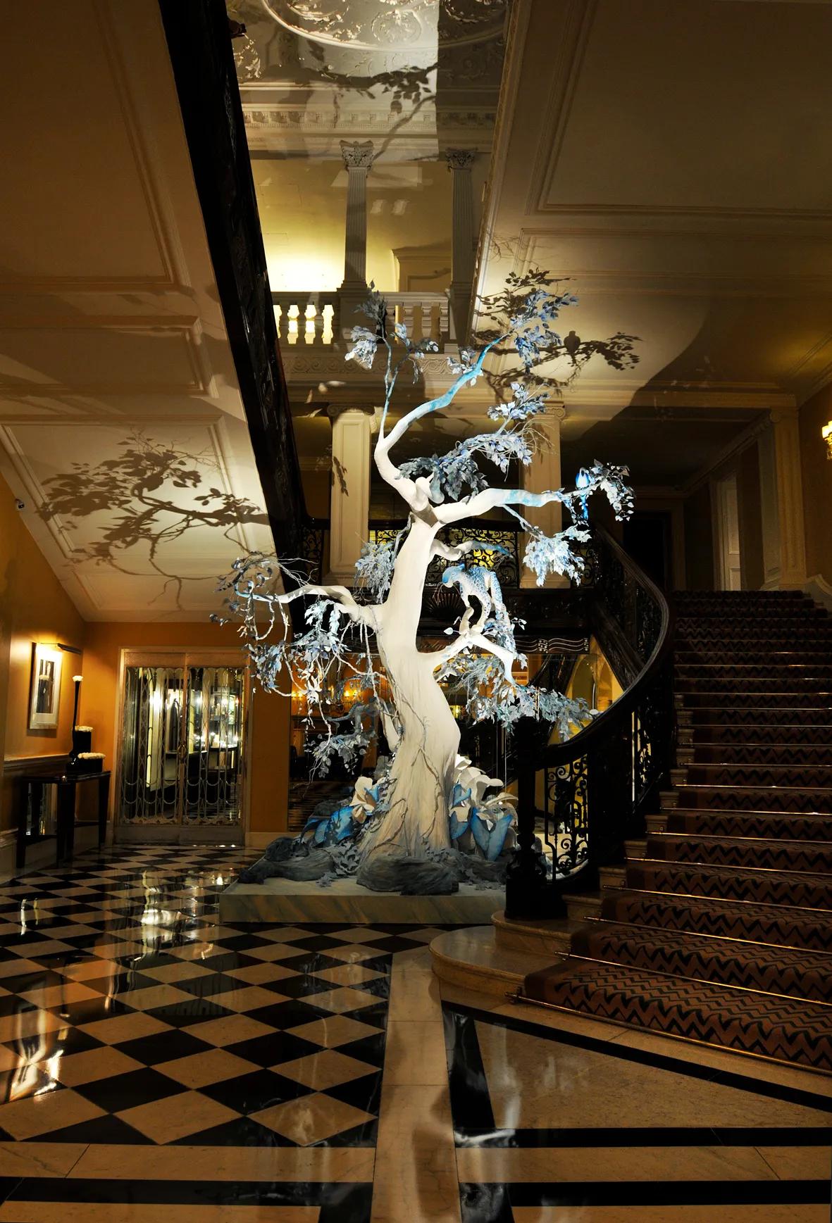 A sculptural white tree installation in Claridge’s lobby beside the grand staircase.