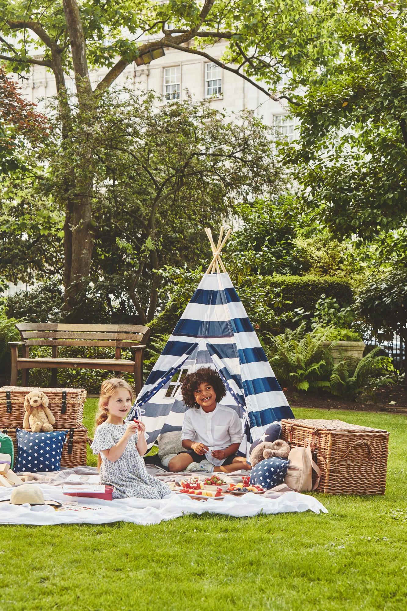 Children playing together outdoors, running and laughing in an open, sunny space.