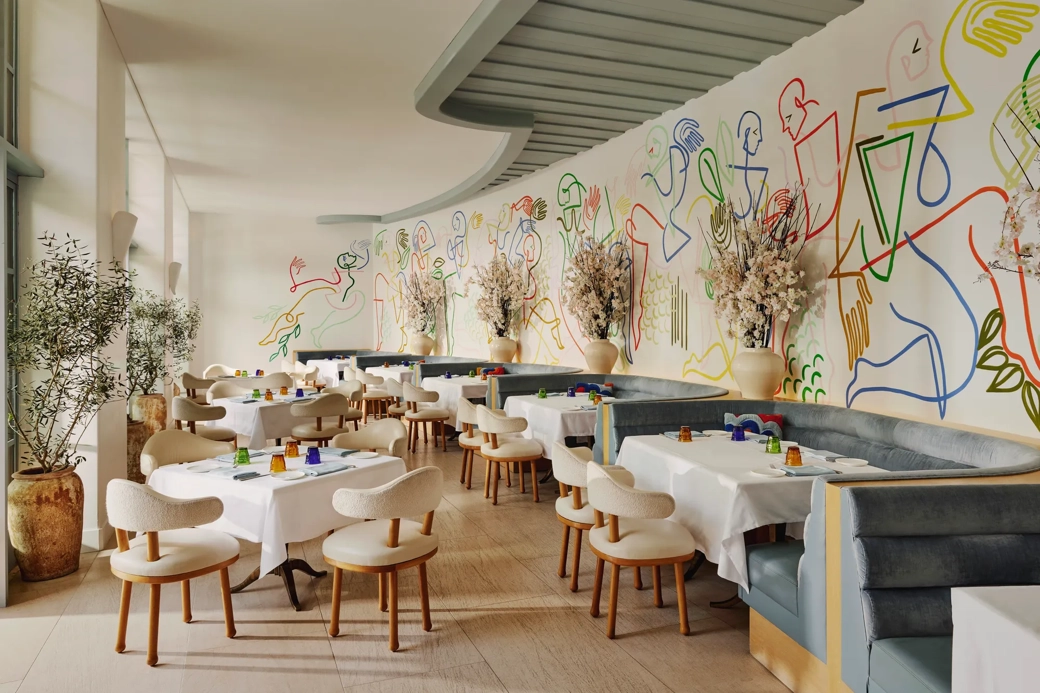 The Terrace dining room with curved banquettes and a colorful line-art mural along the wall.