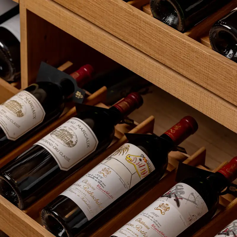 Wine bottles neatly stored in a wooden drawer rack with labels visible.