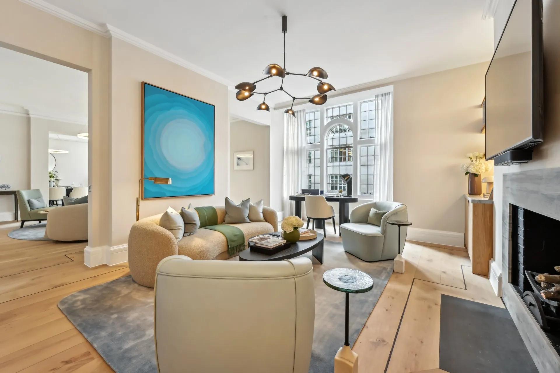 Contemporary living room with curved sofa, bold blue artwork, armchairs, and arched window.